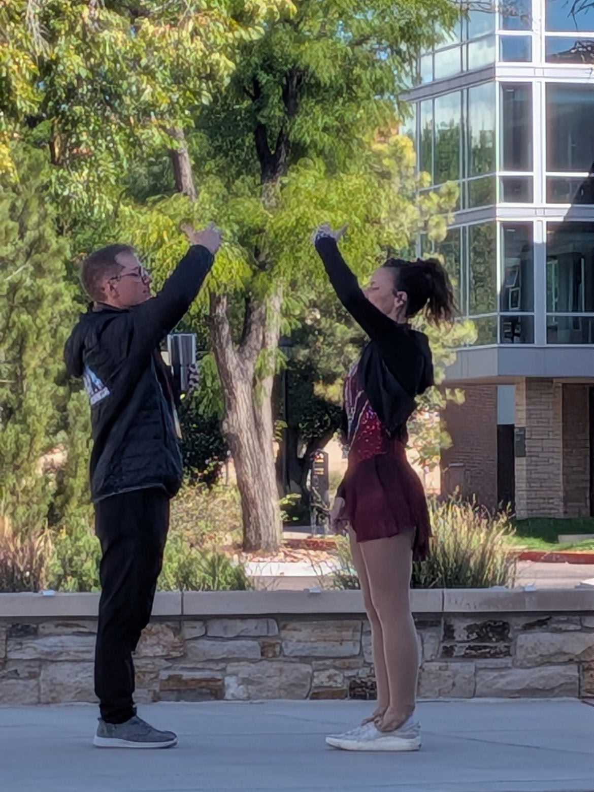 Coach Nick and a figure skater raising their arms together outdoors