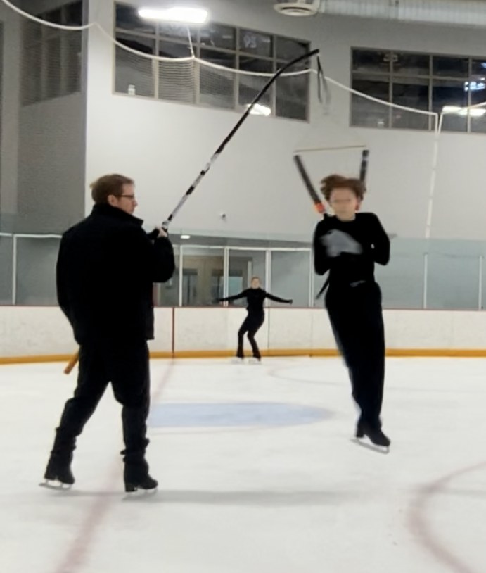 Coach Nick working directly with a figure skater during an on-ice harness lesson